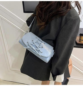 Detail of light blue patent leather bag featuring unique lace-up design and adjustable strap