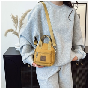 Close-up of bright yellow waterproof nylon crossbody bag with brand logo and front zipper