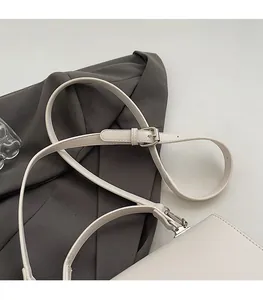 Detail of adjustable white leather shoulder strap with metallic buckle on a square bag