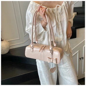 Detail of light pink baguette bag featuring a leather bow and metal heart charm