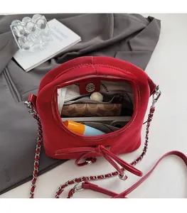 Sac bandoulière en cuir rouge foncé montrant un intérieur spacieux avec poches et objets