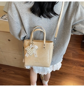 Détail du sac seau plissé beige avec breloque cœur perlé et nœud décoratif en dentelle