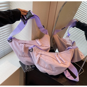 Macro detail of purple nylon crescent bags showing embroidery and plastic buckles