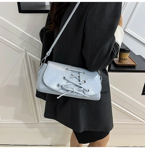 Detail of light blue crossbody bag with corset-style lace-up design and bow detail