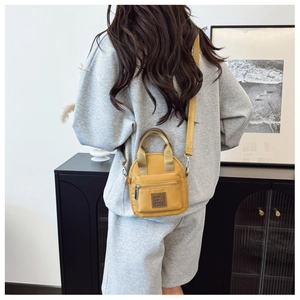 Detail view of a bright yellow waterproof nylon crossbody bag with adjustable shoulder strap