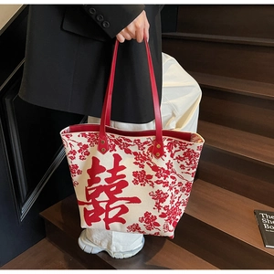 Detail of white canvas tote bag with red Xi character and traditional floral patterns
