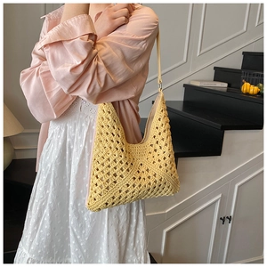 Détail d'un sac à bandoulière au crochet jaune porté par un mannequin en chemise rose