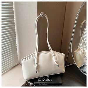 Detailed side view of cream faux leather underarm bag with knot strap and silver accents