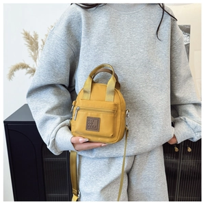 Woman carrying a bright yellow waterproof nylon crossbody bag with dual top handles
