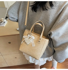 Détail du sac doré champagne avec pendentif cœur perlé et décoration de nœud en dentelle