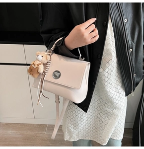 Detail of off-white retro crossbody bag with adjustable strap and cute plush bear charm