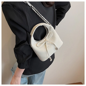 Détail du sac à main blanc crème avec nœud en cuir et bandoulière en chaîne argentée