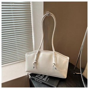 Detail of cream minimalist tote bag with soft leather texture and knot shoulder strap