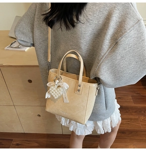 Détail du sac seau blanc crème avec pendentif cœur perlé et nœud en dentelle