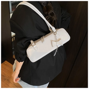 Close-up of a white baguette shoulder bag with a 3D bow and elegant metal chain strap