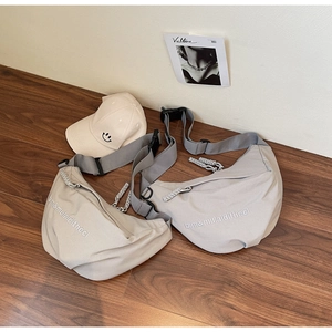 Flat lay of minimalist crescent crossbody bags in beige and grey with embroidery