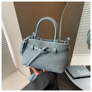 Close-up of light blue textured bucket bag with silver hardware and leather handle detail