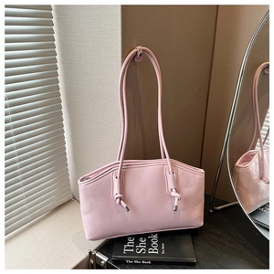 Detail shot of a pink leather shoulder bag with decorative knots and metallic tips