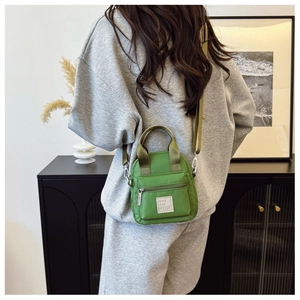 Rear view of model wearing a light green waterproof nylon crossbody bag with dual handles