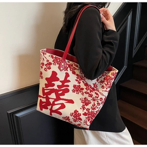 Detail of knitted tote bag with red Xi character and floral patterns on ivory base