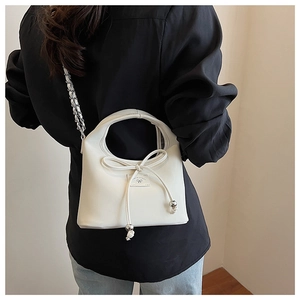 Détail du sac à bandoulière en cuir blanc avec nœud décoratif et sangle en chaîne