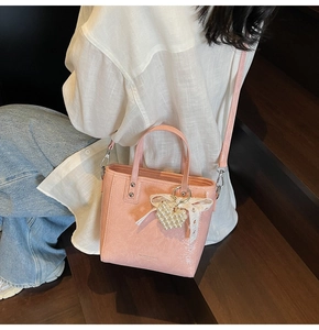 Détail du sac à main rose avec breloque cœur en perle et nœud en dentelle sur escalier