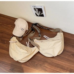 Beige crescent canvas bags and matching smiley face baseball cap on dark wood floor