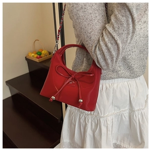 Détail du sac à main en cuir verni rouge avec finition brillante et décoration de nœud