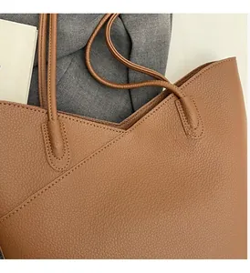 Close-up of caramel brown tote bag showing litchi grain leather texture and neat stitching