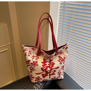 Close-up of beige tote bag featuring red Double Happiness pattern and leather handles