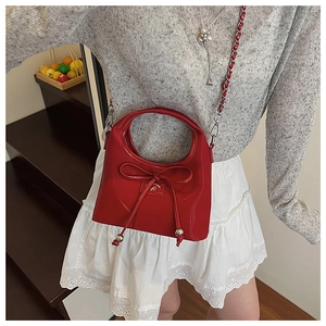 Détail d'un sac à main rouge brillant avec poignée ronde et nœud élégant