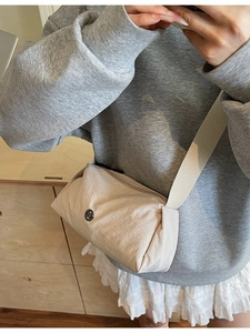 Minimalist beige nylon crossbody pillow bag with wide strap and metallic logo