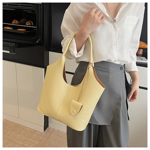 Close-up of yellow leather hobo bucket bag with small charm pouch and lychee grain texture