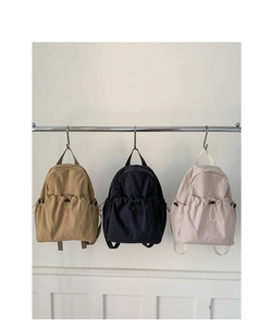 Three minimalist nylon backpacks in khaki, black, and beige with drawstring pockets