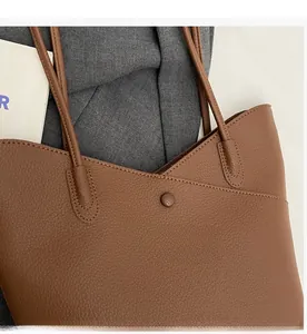 Detail shot of brown lychee-textured tote bag showing magnetic snap and fine stitching