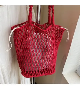 Detail of red hollowed-out knit tote bag with gray drawstring liner and braided handle