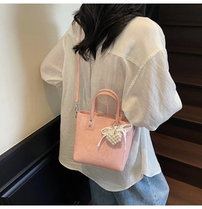 Détail du sac seau en cuir gaufré rose avec breloque cœur perle et nœud en soie