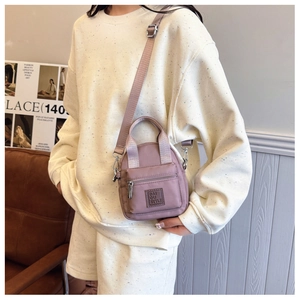 Close-up of nylon mini crossbody bag in dusty rose featuring adjustable straps
