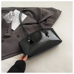 Detail of black glossy patent leather shoulder bag with sleek cylindrical knot handles