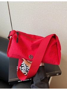 Minimalist red nylon crossbody pillow bag with metal M logo and wide strap for women