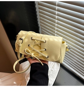 Detailed macro view of cream yellow leather shoulder bag with corset lace-up design