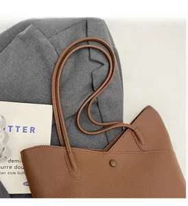 Close-up of brown litchi pattern leather tote bag with metallic magnetic buckle detail