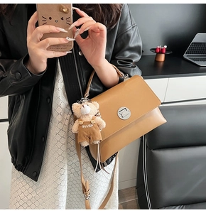 Detail of camel leather handbag with metal twist lock and cute teddy bear charm