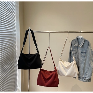 Minimalist canvas tote bags in black, burgundy, and off-white shown with denim jacket