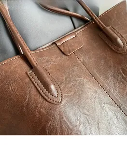 Detailed shot of reinforced shoulder strap stitching on a vintage brown leather tote bag