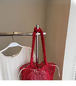 Detail of red knitted tote bag with thick braided strap and white drawstring inner bag