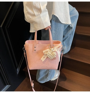 Sac seau rose avec texture plissée, nœud en dentelle et breloque cœur perlé