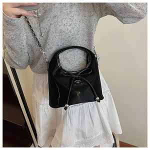 Détail d'un sac à main noir en nylon avec noeud décoratif et chaîne argentée