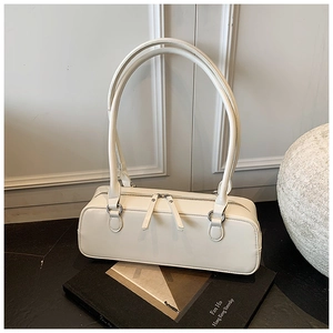 Detailed view of white leather baguette bag with silver hardware on a marble surface