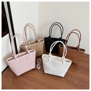 Detail of woven tote bags with knot handles and detachable straps in five colors